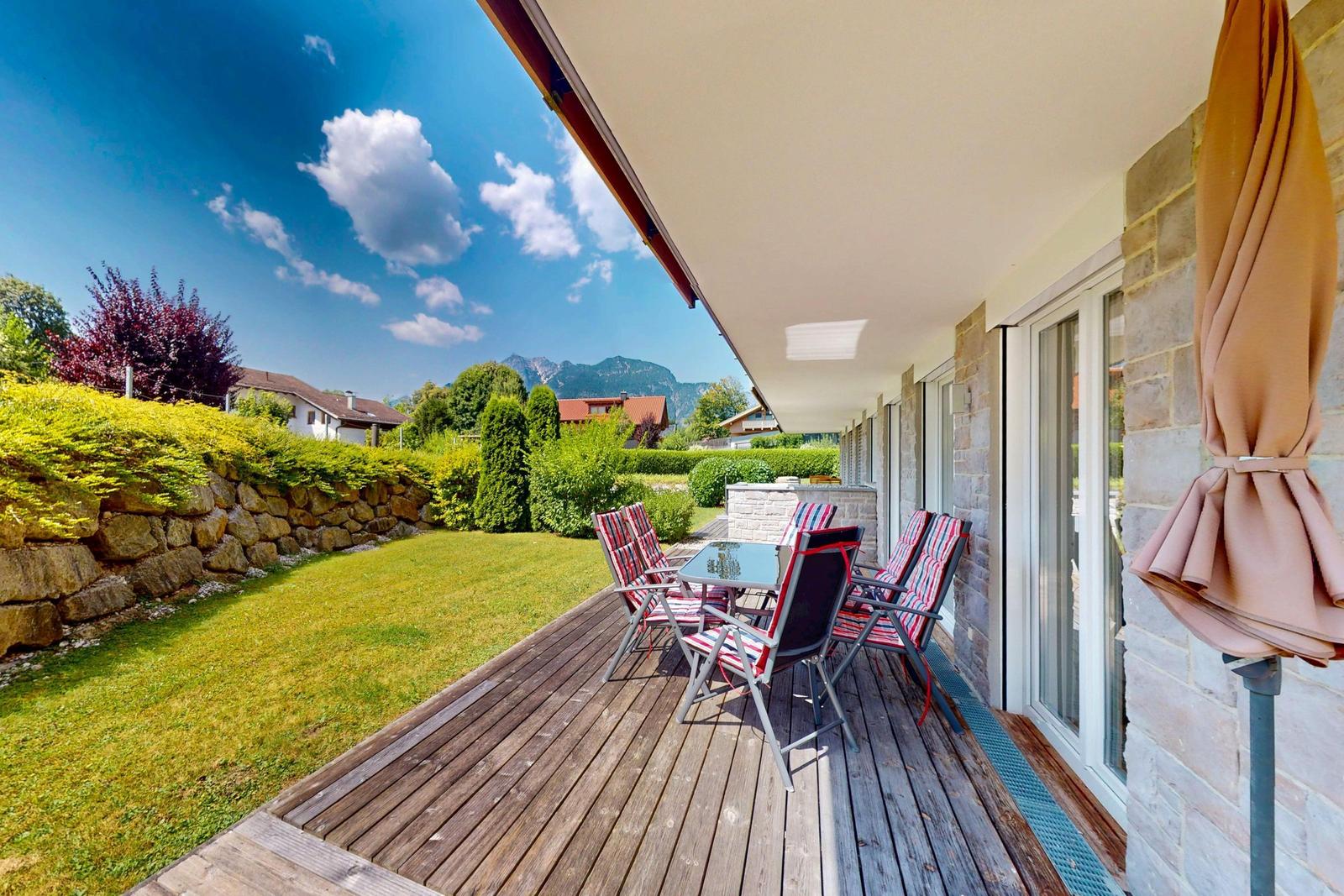 Terrasse mit Sitzgruppe, Garten und Bergblick.