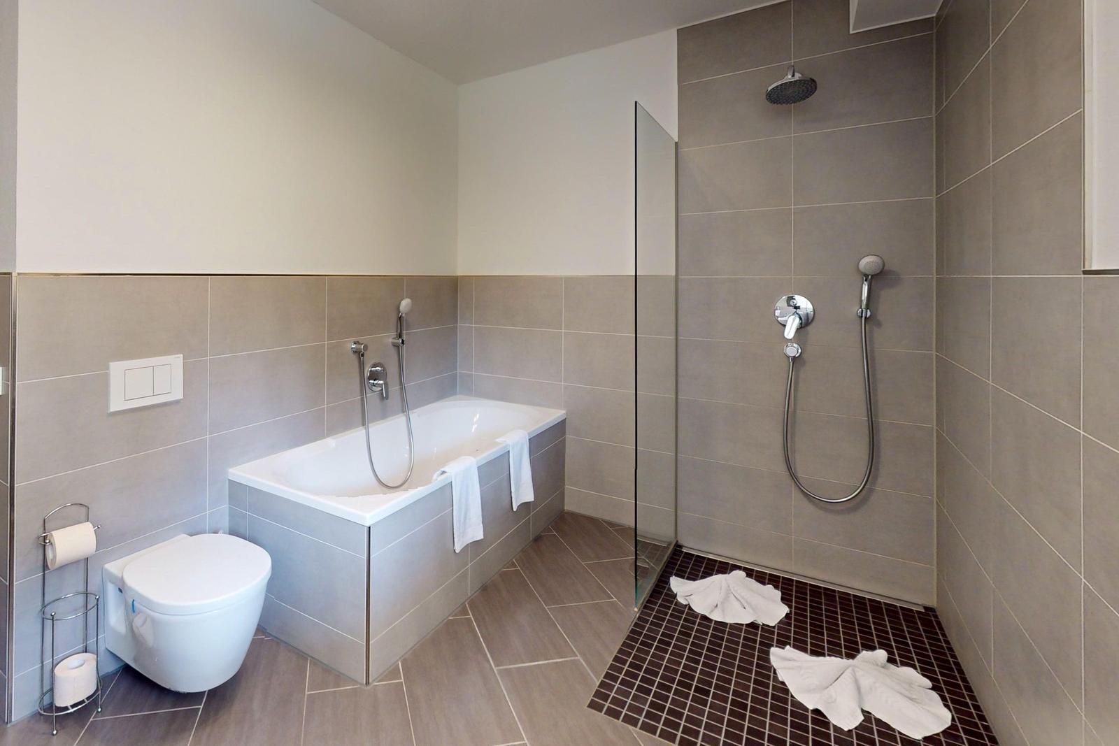 Badezimmer mit Badewanne, Dusche und Toilette.