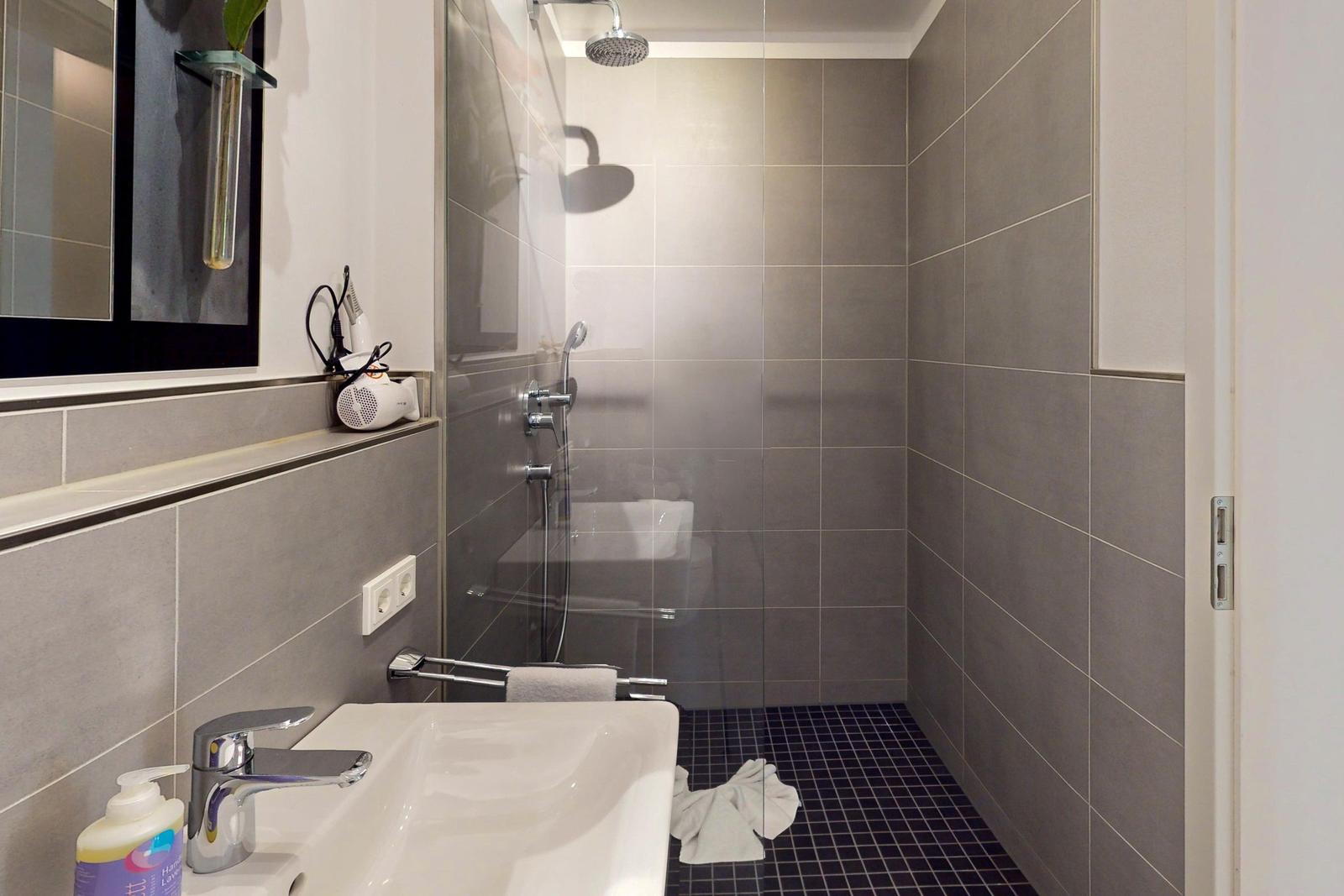 Badezimmer mit Dusche, Waschbecken und Handtuchhalter