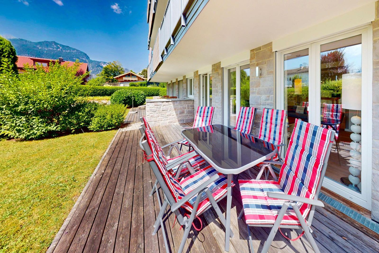 Terrasse mit Tisch und Stühlen, Blick auf Grün und Berge.