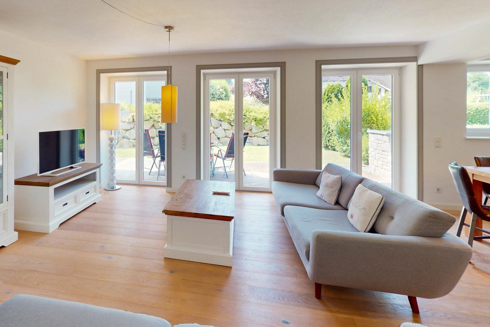 Wohnzimmer mit Sofa, TV und Terrassenzugang