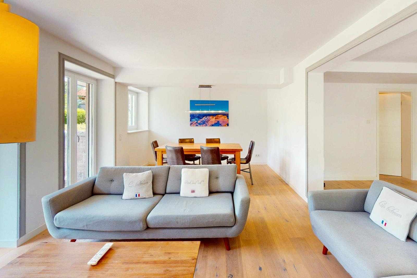 Wohn- und Essbereich mit Sofa, Tisch und Stühlen.