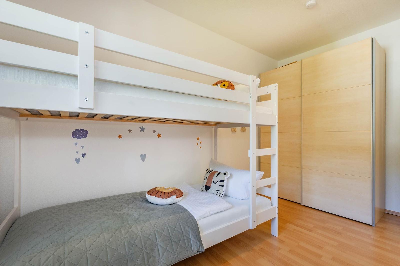 Kinderzimmer mit Doppelstockbett, Kleiderschrank und Wanddekoration.