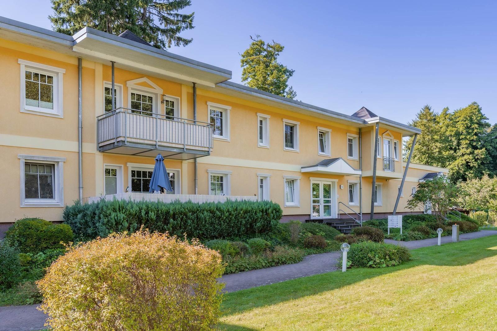 Ein gelbes Haus mit Balkon und Gartenweg.