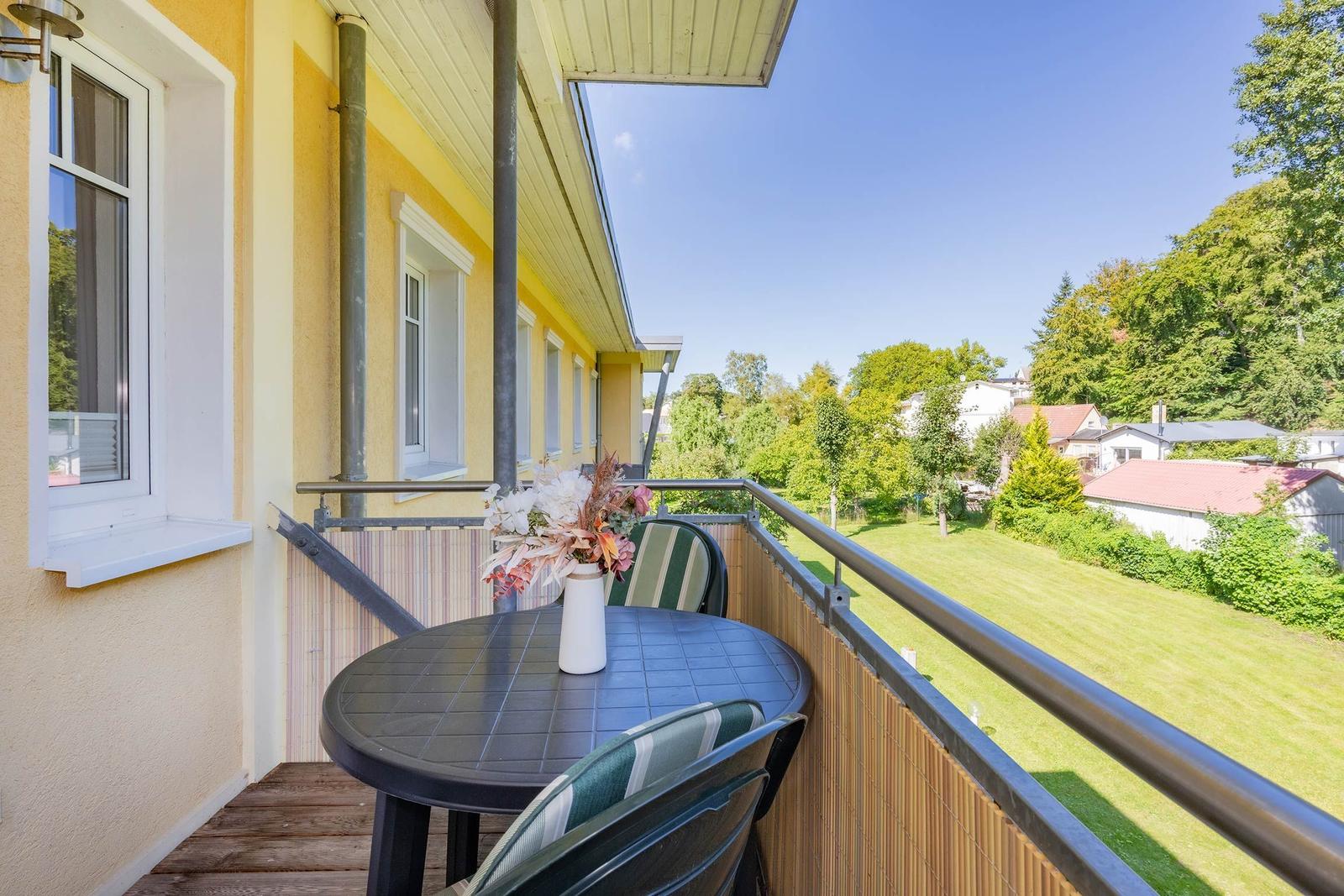 Terrasse mit Tisch und Stühlen, Blick auf grünen Garten und Bäume.