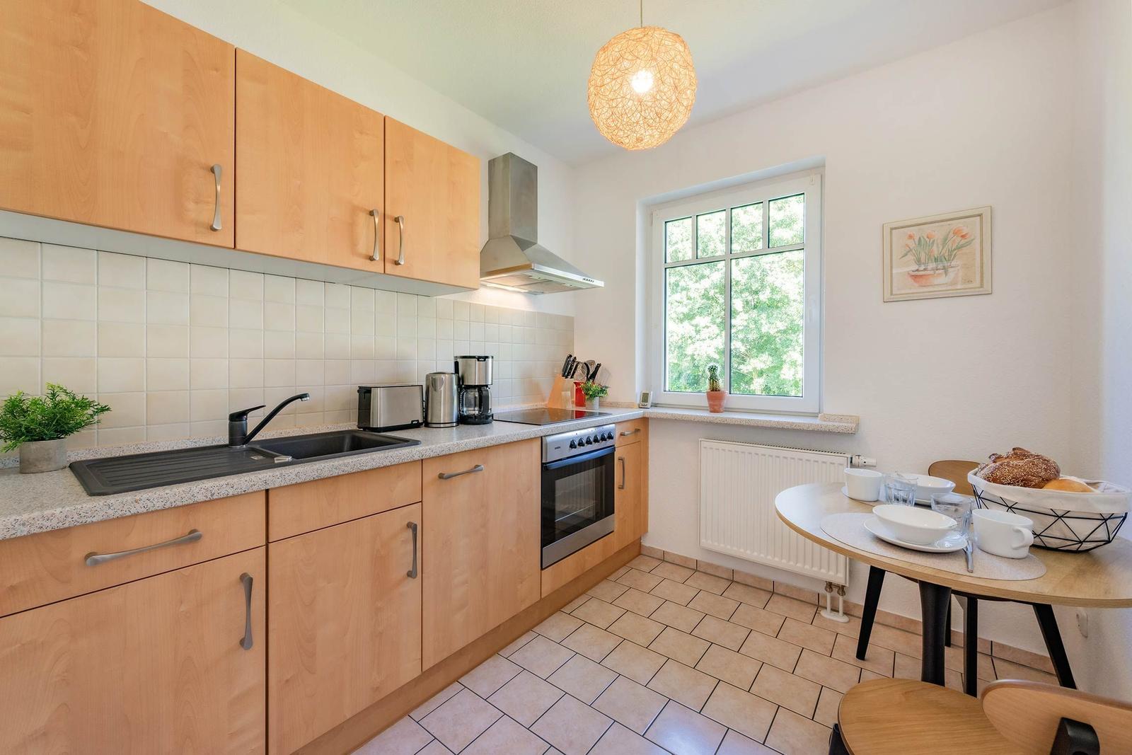 Küche mit Essbereich, Fenster, Küchengeräten und Tisch mit Tassen.