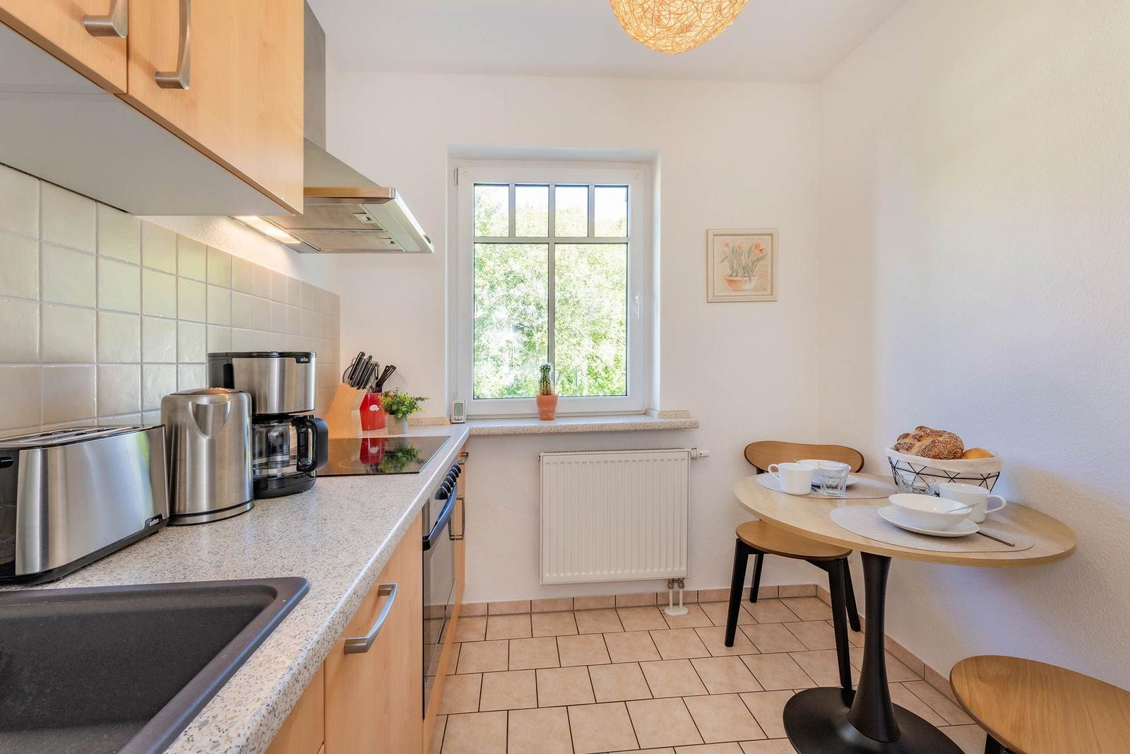 Küche mit Essbereich, Fenster, Arbeitsplatte und Küchengeräten.