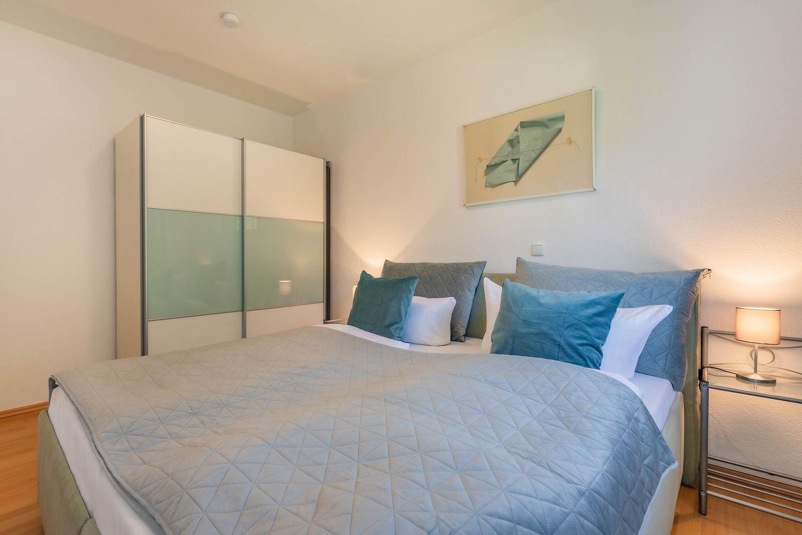 Schlafzimmer mit Bett, Nachttisch und Kleiderschrank.