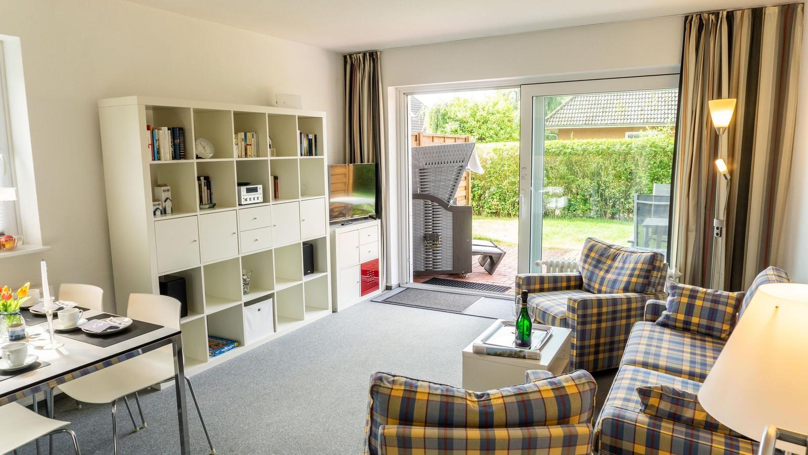 Wohn- und Essbereich mit Bücherregal, TV und Balkontür.