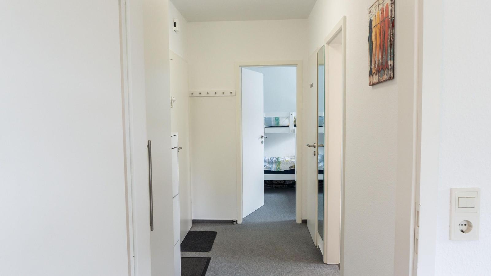Flur mit Schlafzimmer und Kleiderhaken. Wandbild und Steckdose sichtbar.