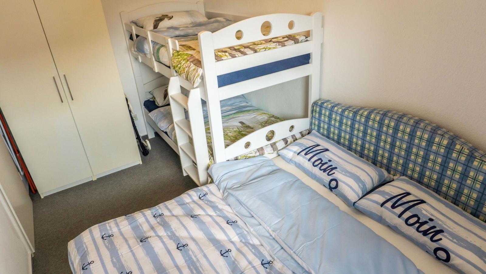 Zimmer mit Doppelbett, Schlafcouch und Kinderstockbett mit Matratzen.