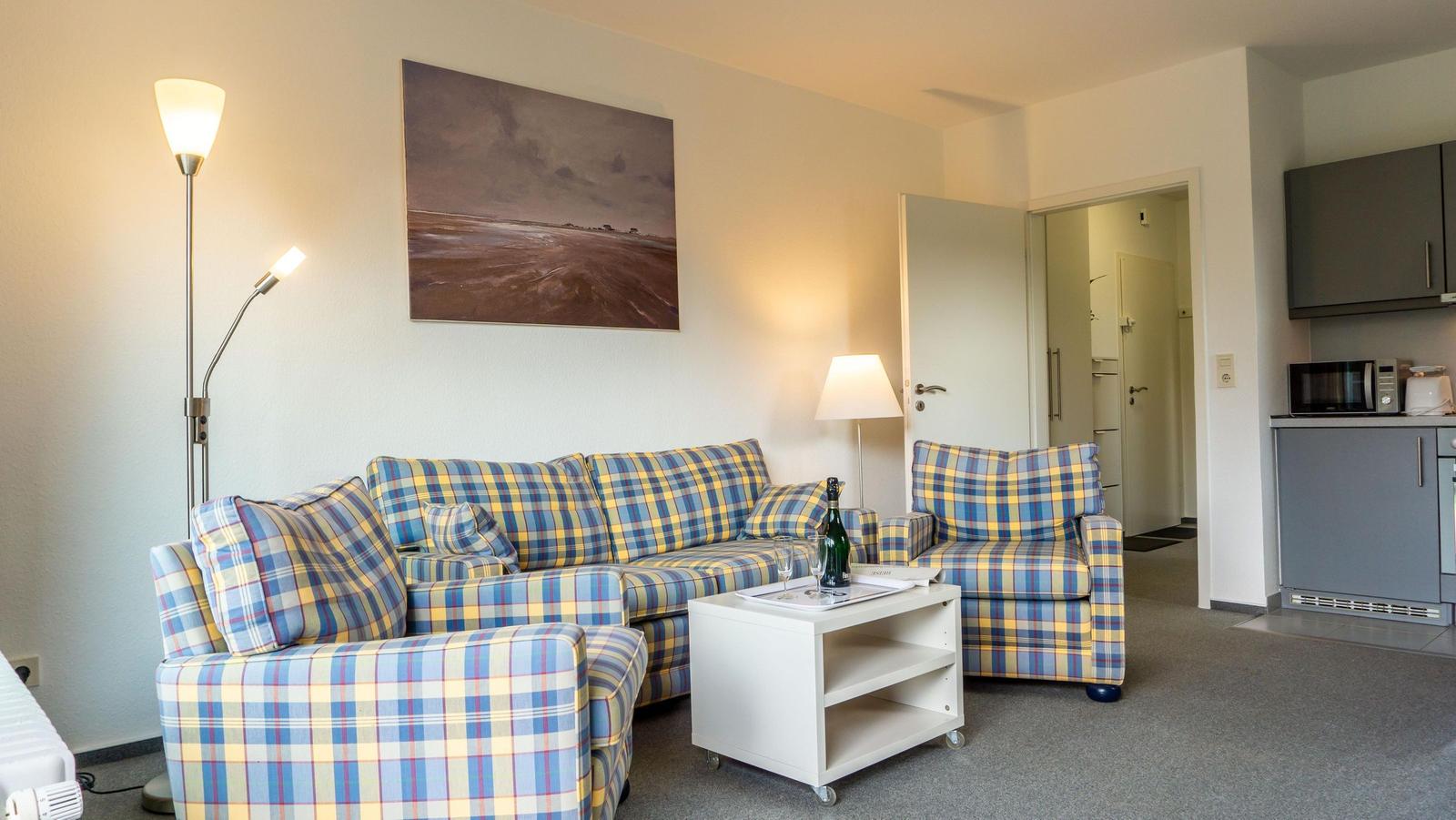 Wohnbereich mit Sofa, Couchtisch und Küchenzeile