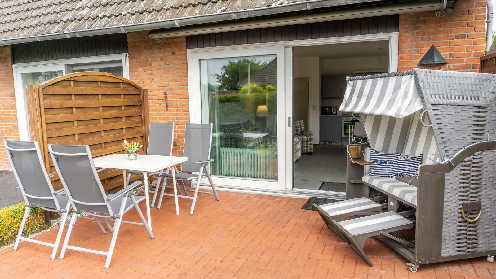 Terrasse mit Sitzgruppe, Strandkorb und Blick in die Küche.