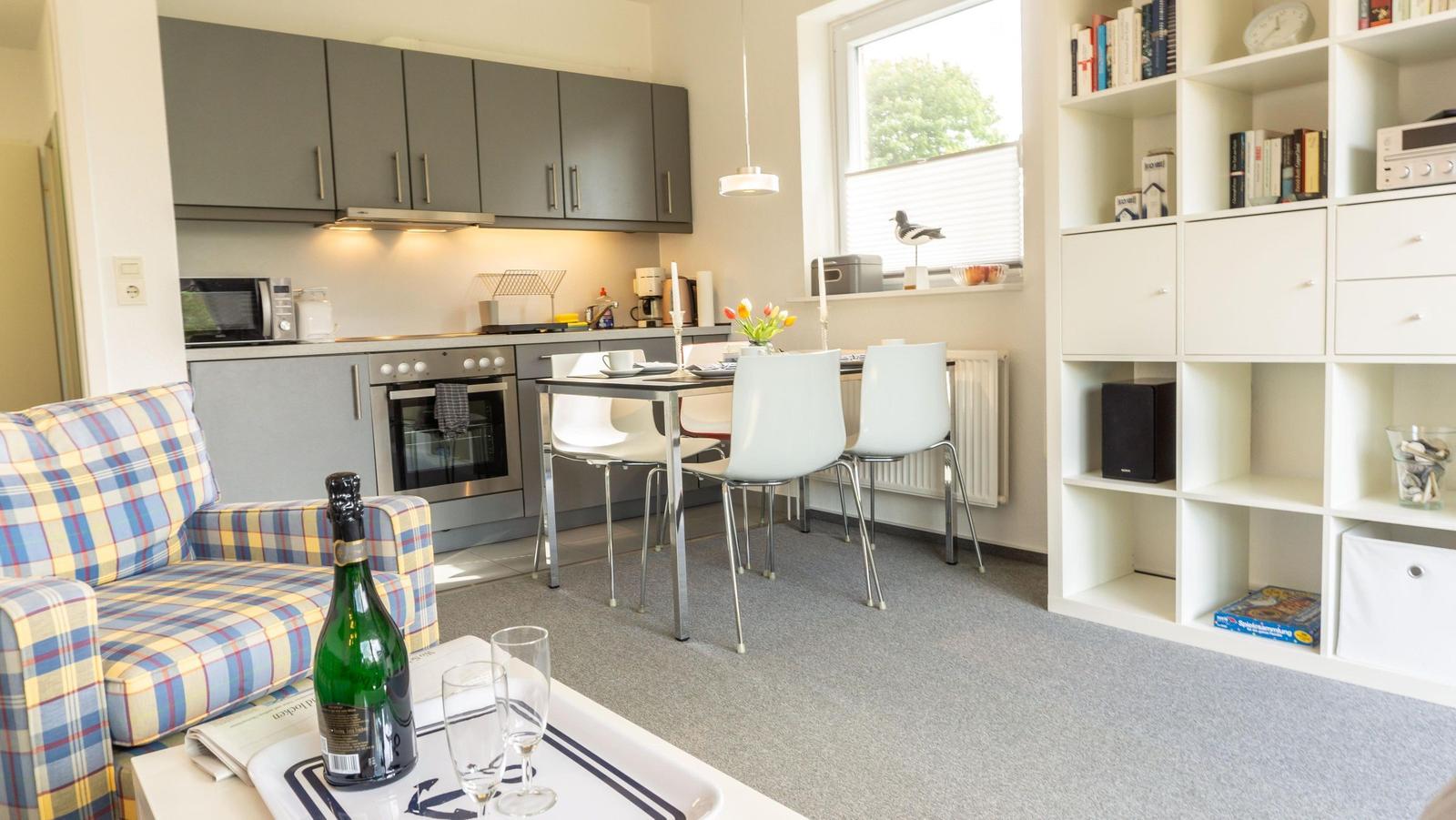 Küche, Essbereich und Wohnbereich mit Sofa, Tisch und Bücherregal.