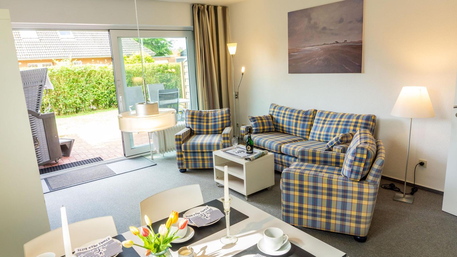 Wohnzimmer mit Plaidsofa, Esstisch und Terrassenzugang.