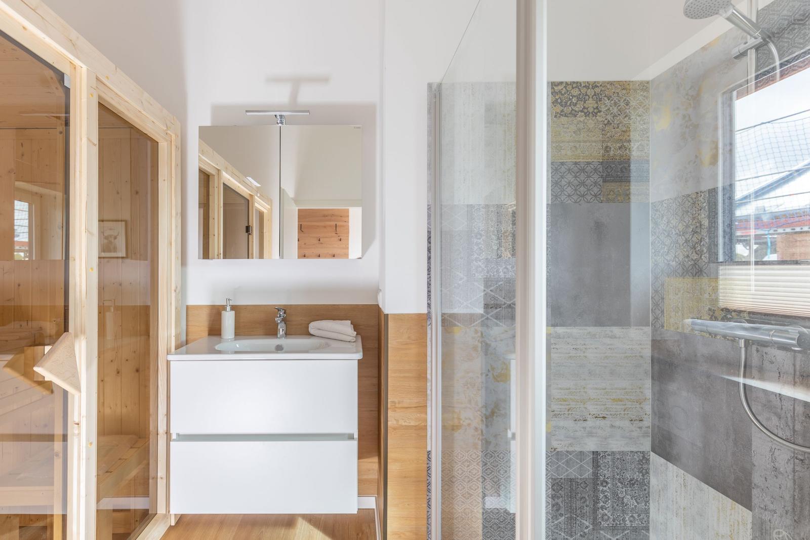Badezimmer mit Dusche, Waschbecken und Sauna