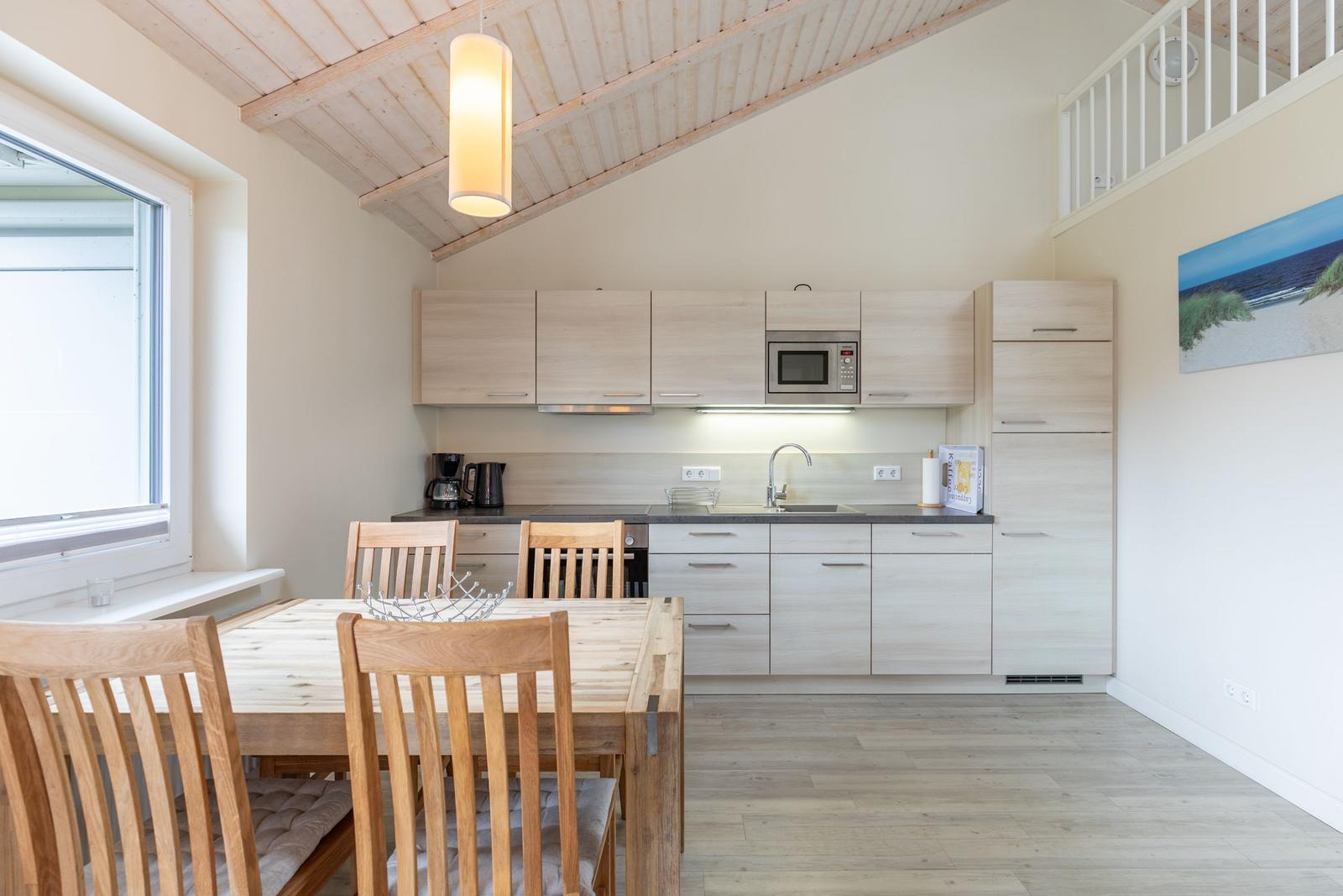 Küche mit Essbereich, Holztisch, Stühle und Mikrowelle.