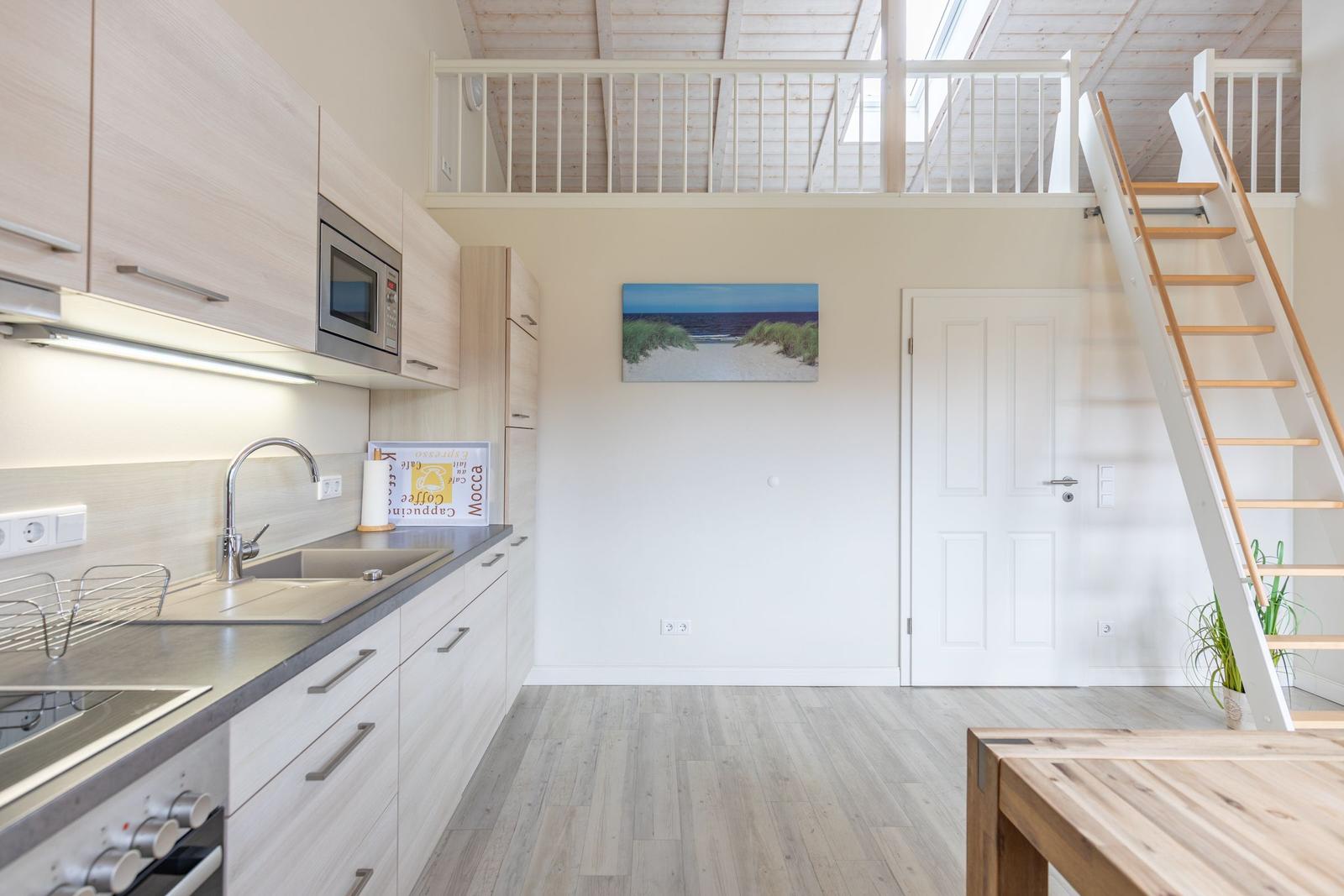 Küche mit Hochbett, Treppe und Küchenzeile.