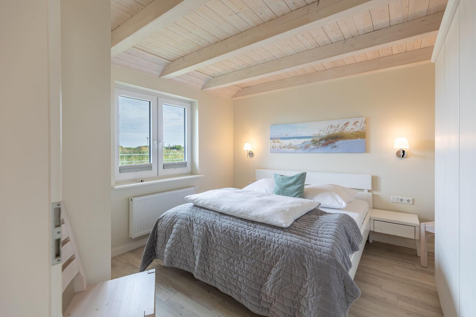 Schlafzimmer mit Bett, Fenster und Deckenbalken.