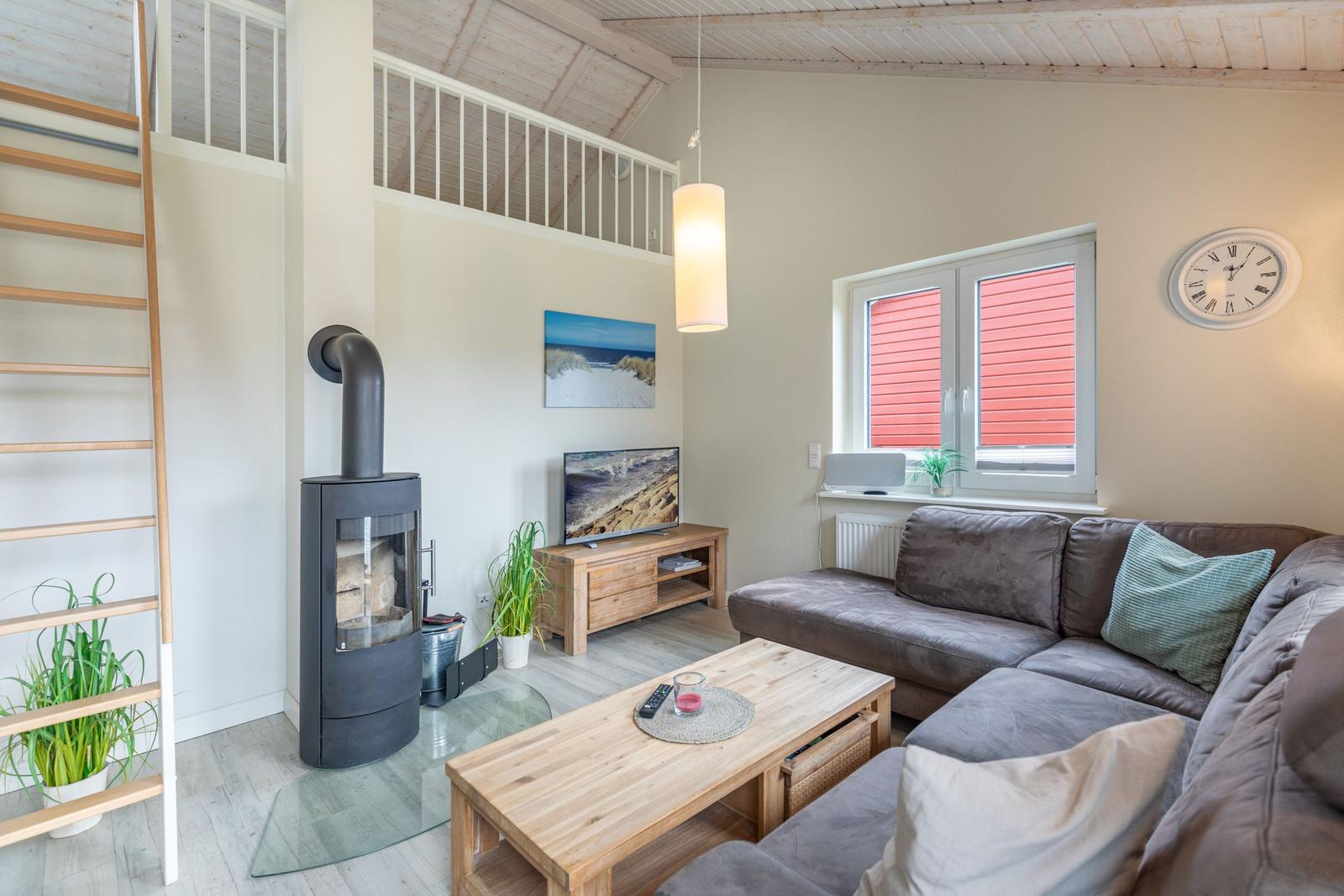 Wohnzimmer mit Sofa, Kamin und Fenster mit roten Jalousien.