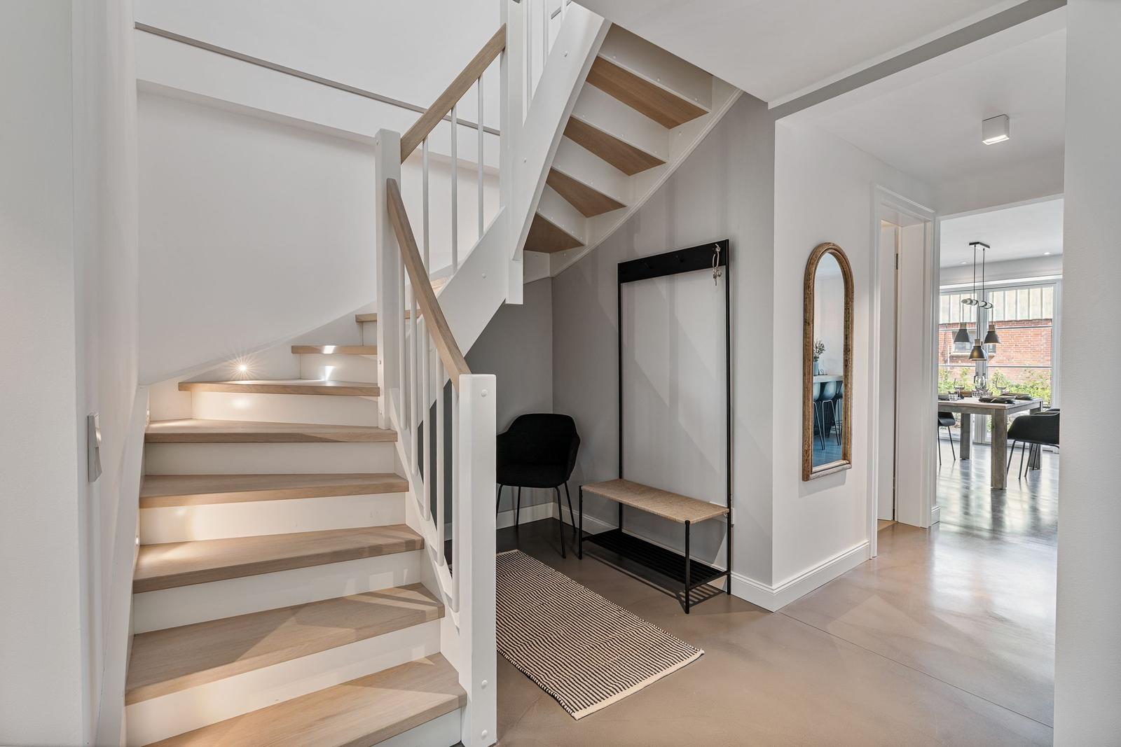 Haus mit Treppe, Garderobe und Spiegel. Durchgang zu Essbereich mit Tisch und Stühlen.