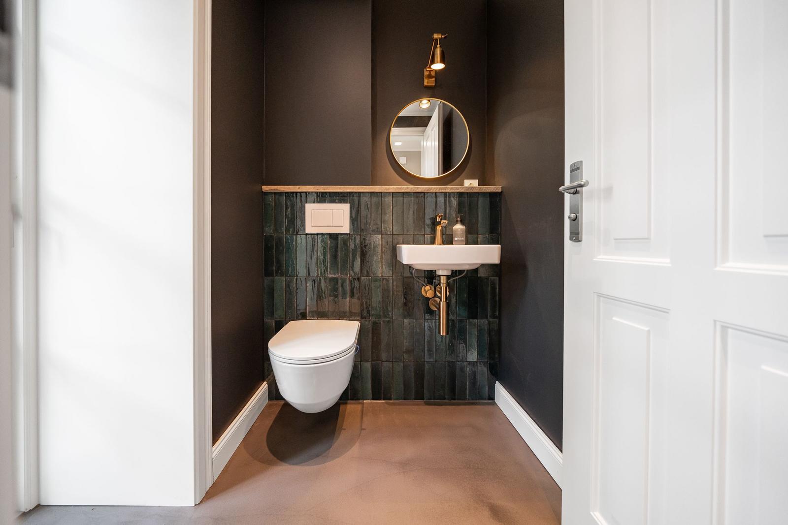 Hochwertige Toilette und Waschbecken mit Spiegel und goldfarbenen Armaturen.