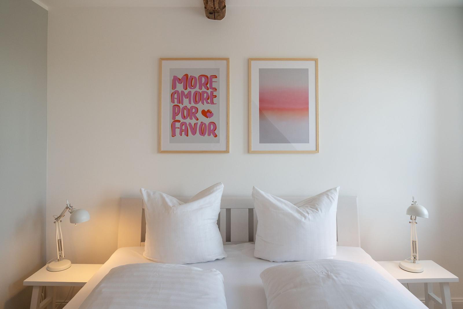 Ein Bett mit weißen Kissen und zwei Nachttischen mit Lampen.