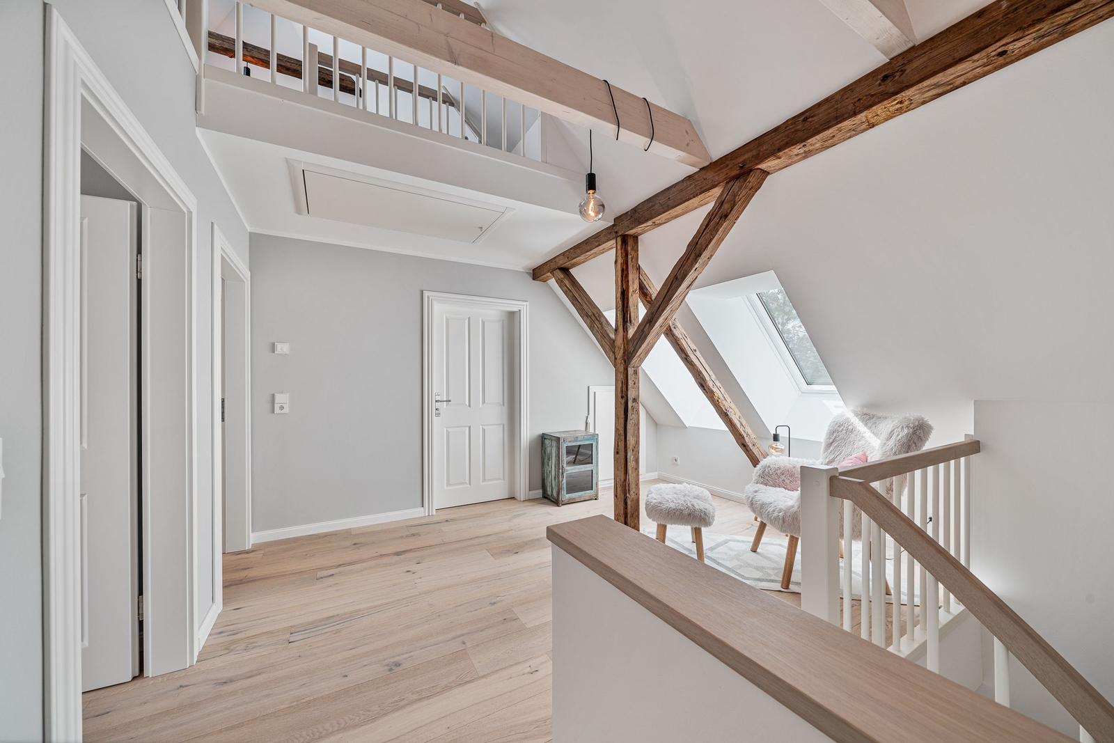 Haus mit Holzdeckenbalken, Treppenhaus und Dachfenster. Flur mit Holzboden und Türen.
