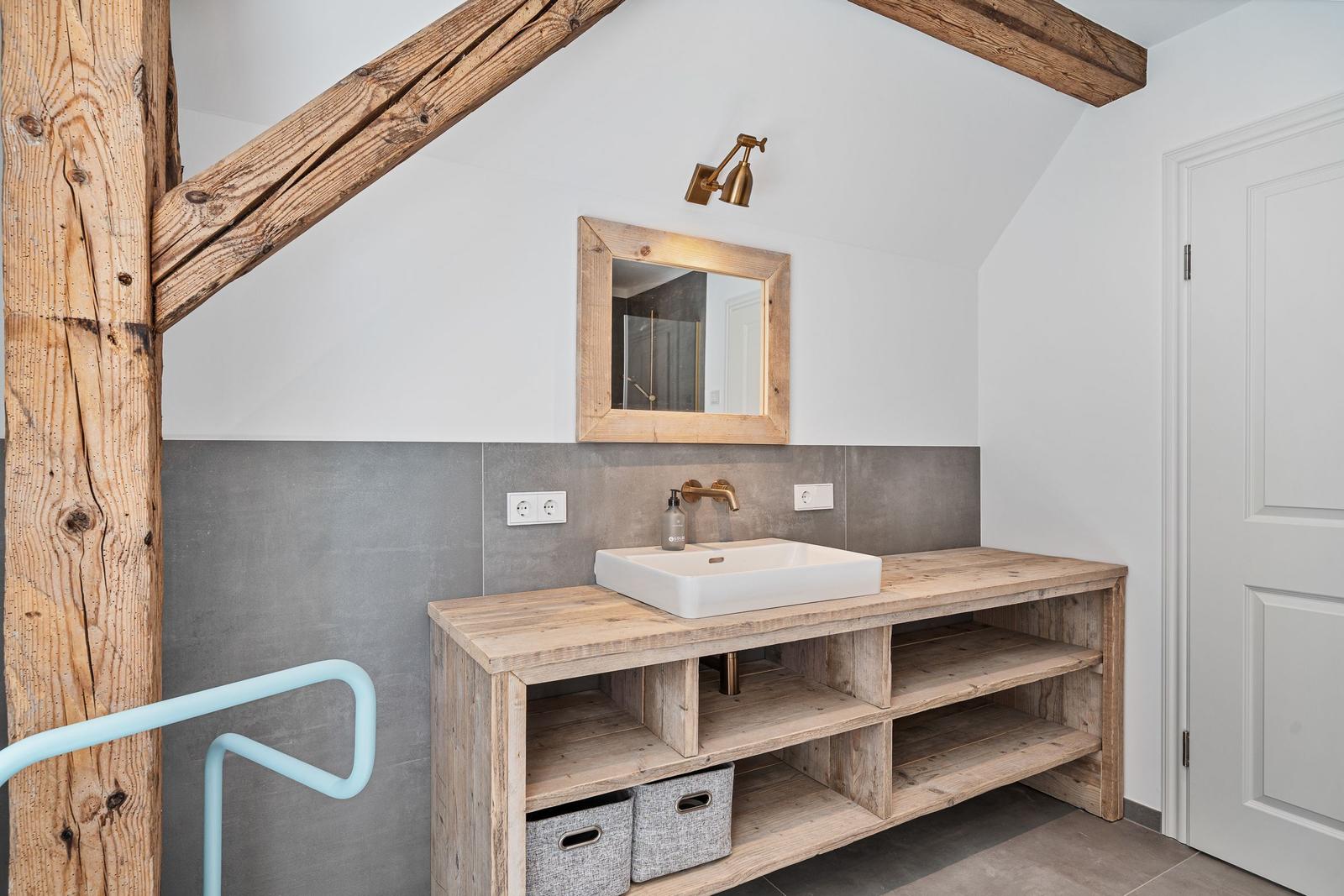 Badezimmer mit Holzwaschtisch, Spiegel und Dachschrägen.