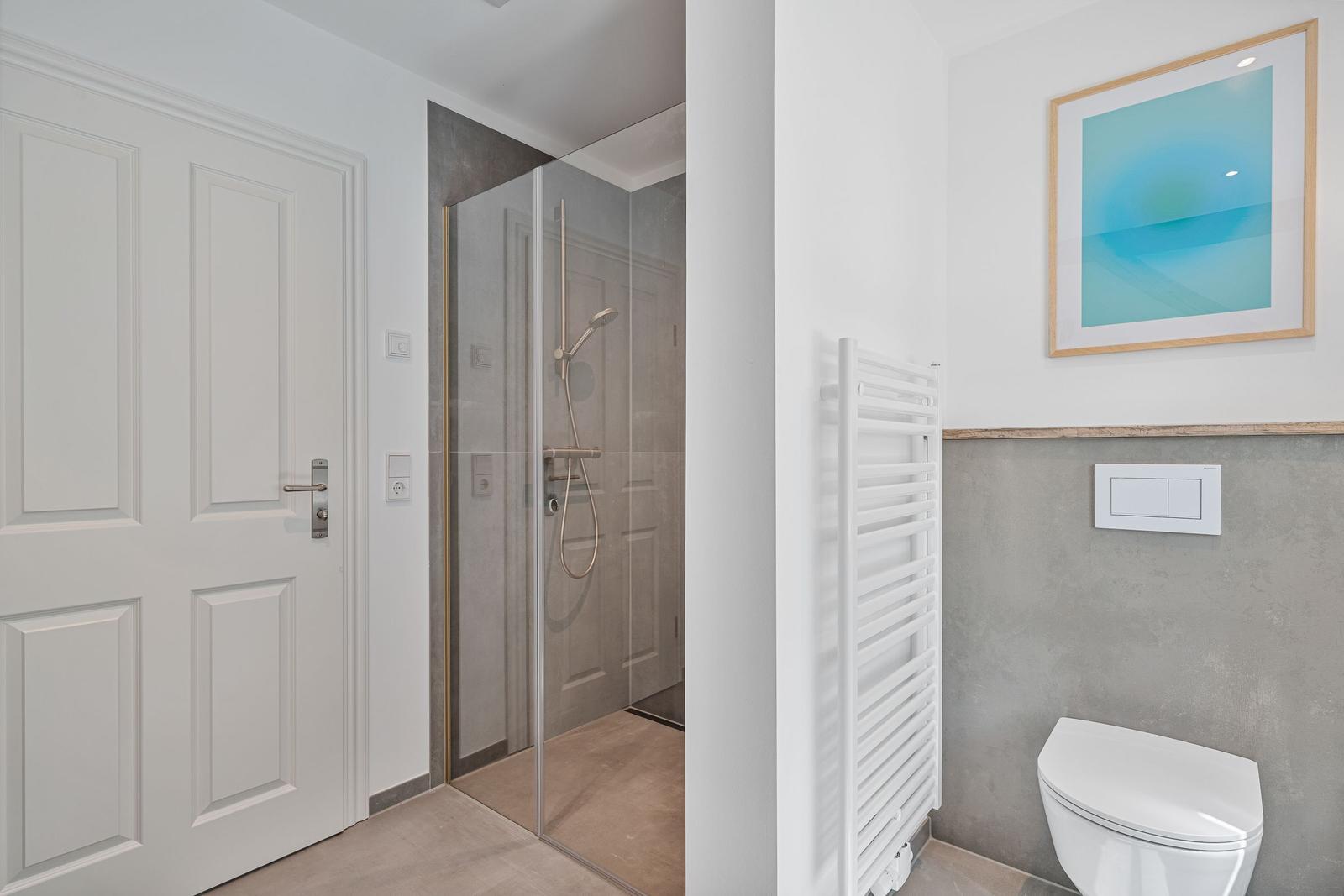 Badezimmer mit Dusche, Toilette und Heizkörper.