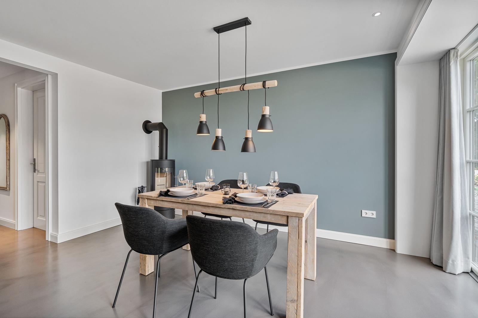 Esszimmer mit Holztisch, schwarzen Stühlen und moderner Hängelampe.