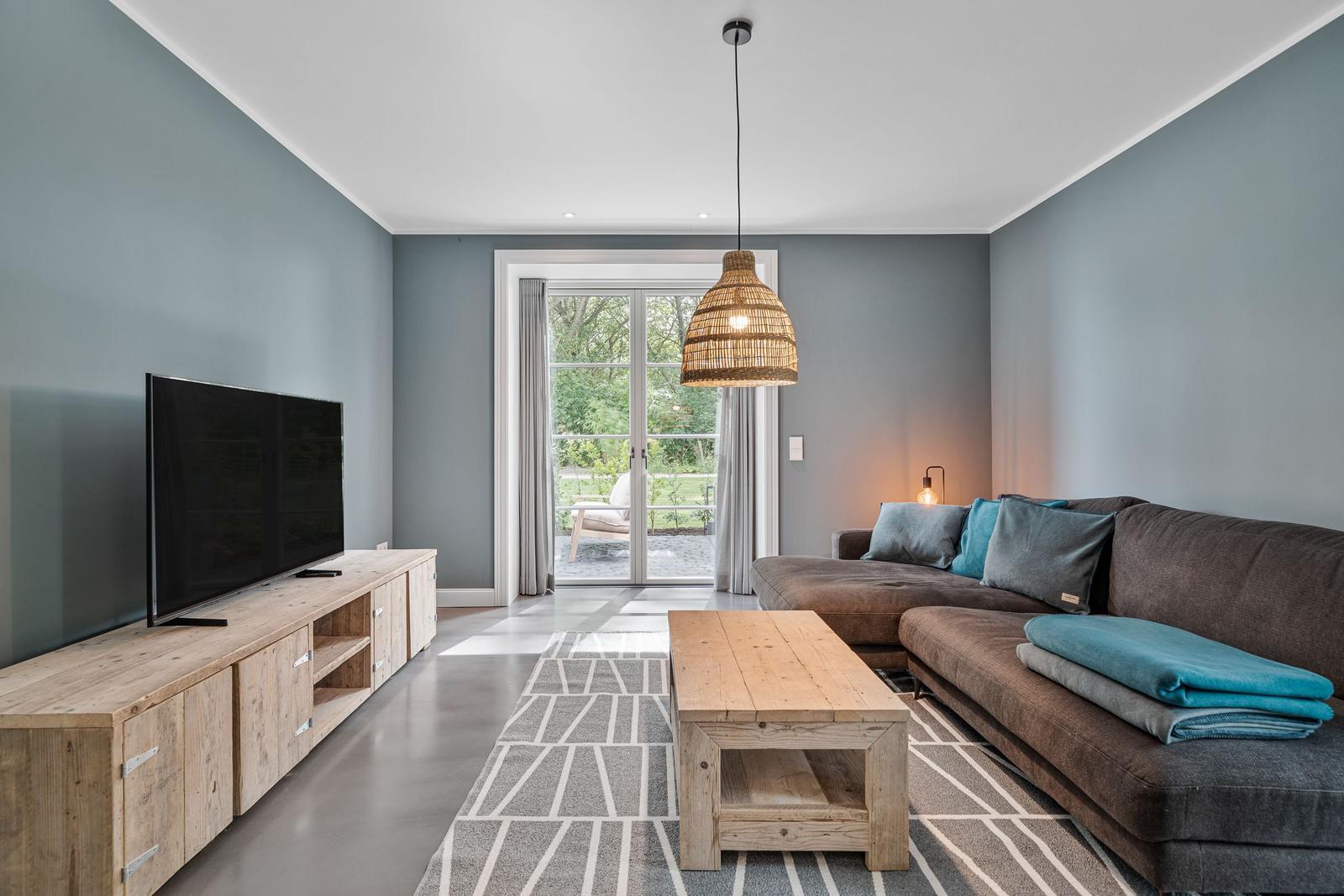 Wohnzimmer mit Sofa, Fernseher und Terrassentür.