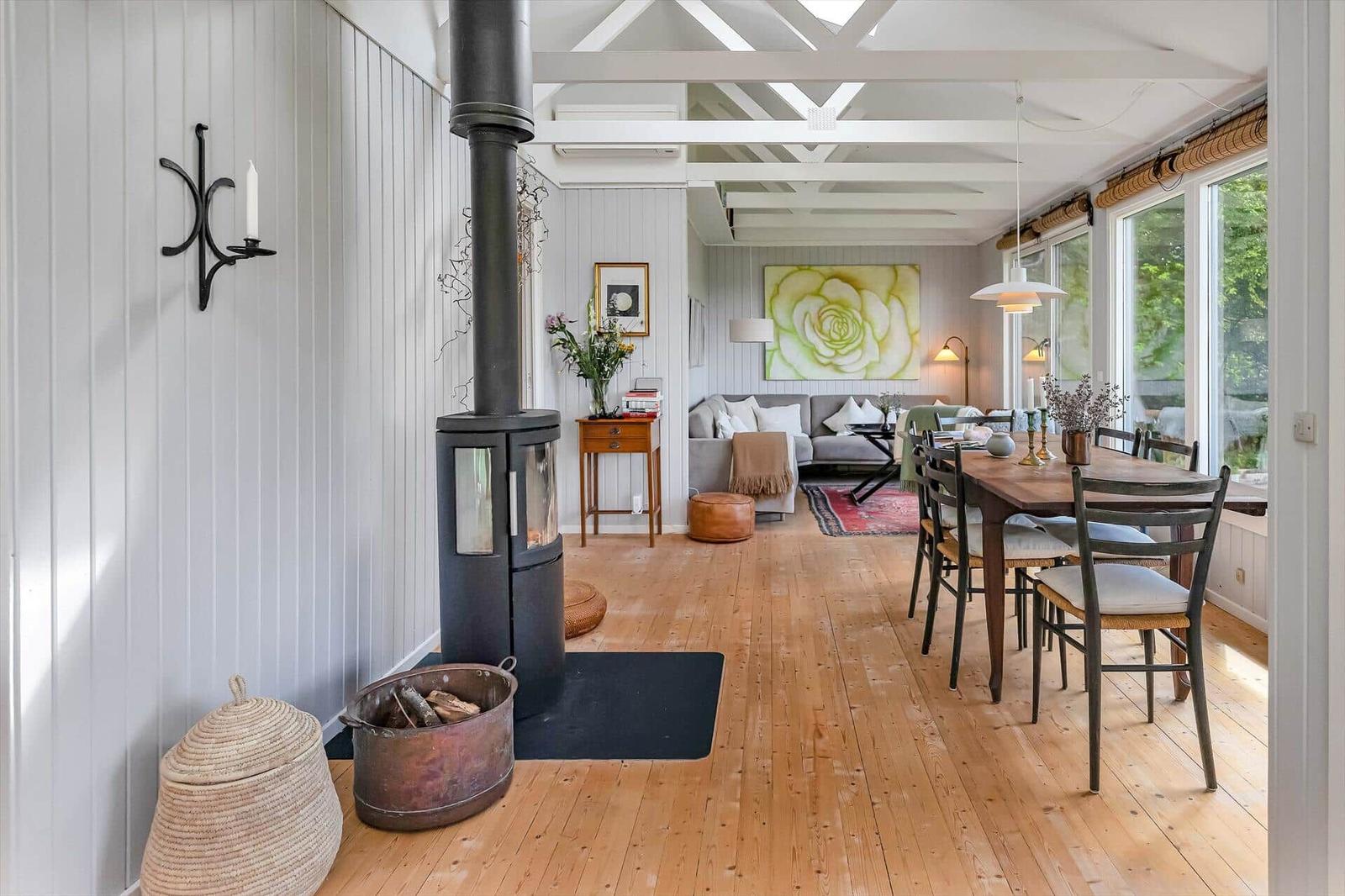 Wohn- und Essbereich mit Holzboden, Kamin und großem Fenster