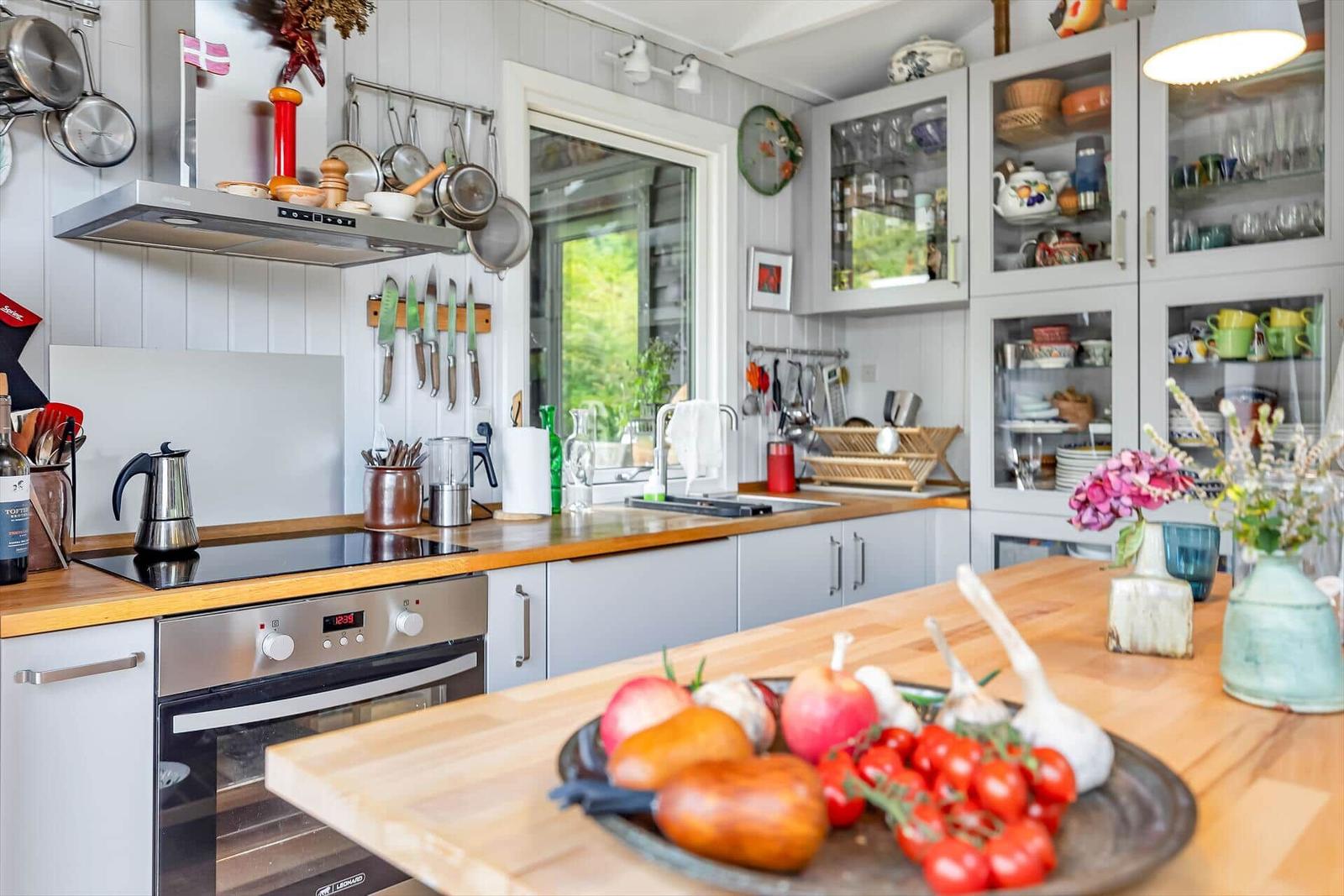 Küche mit Holzoberflächen, Edelstahlgeräten und Glasvitrinen mit Geschirr.