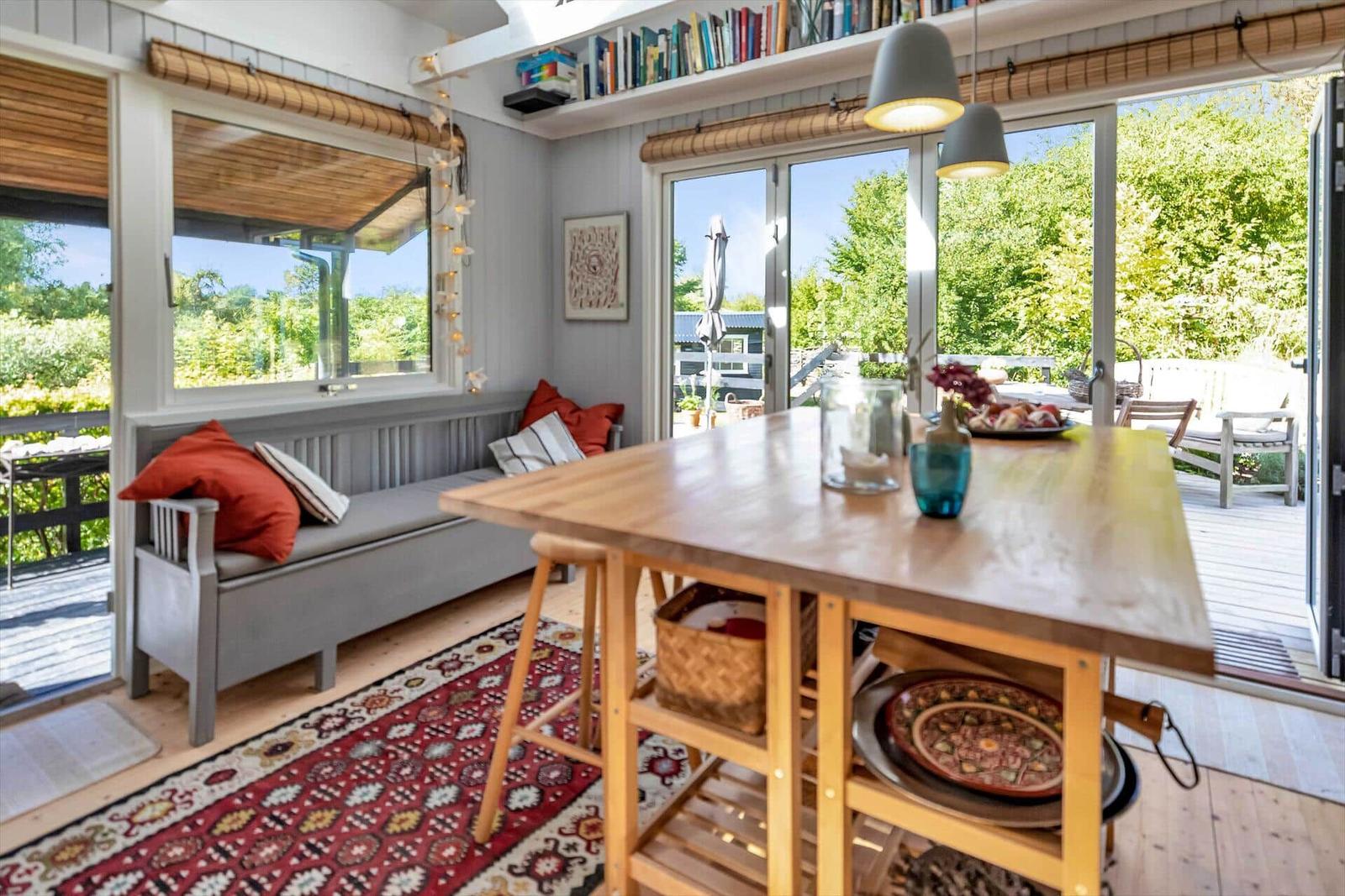Ein Raum mit Holztisch, Sofa und Blick auf die Terrasse.