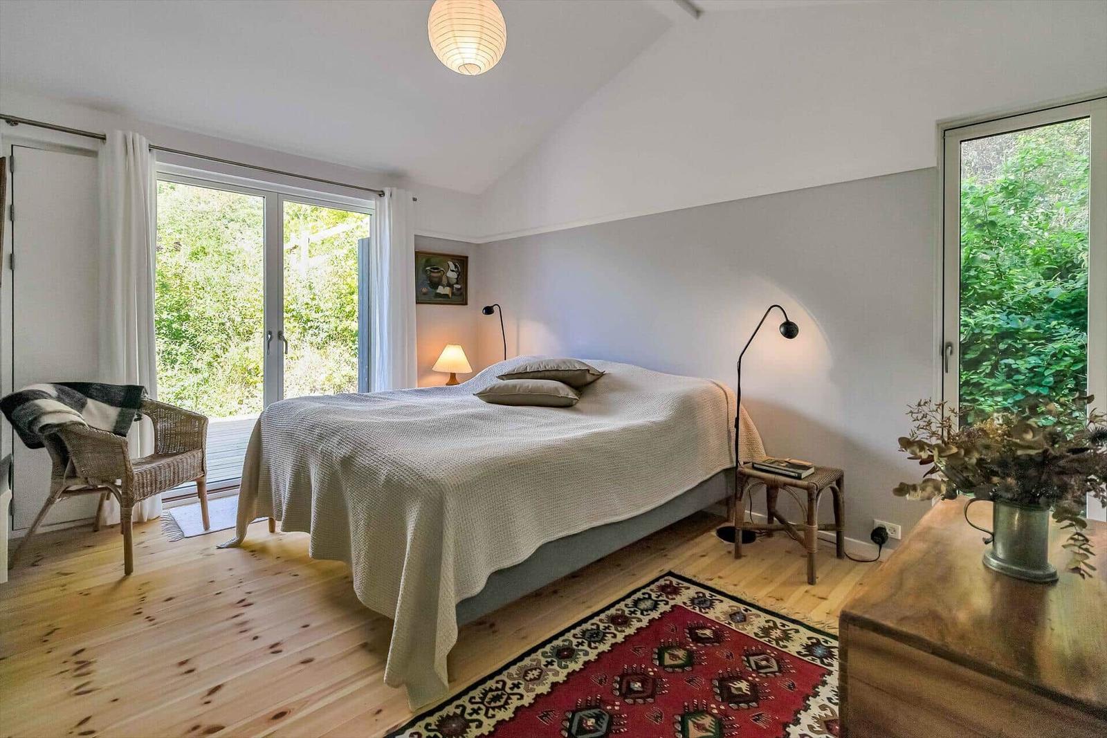 Schlafzimmer mit Bett, Fenstern und Holzboden.