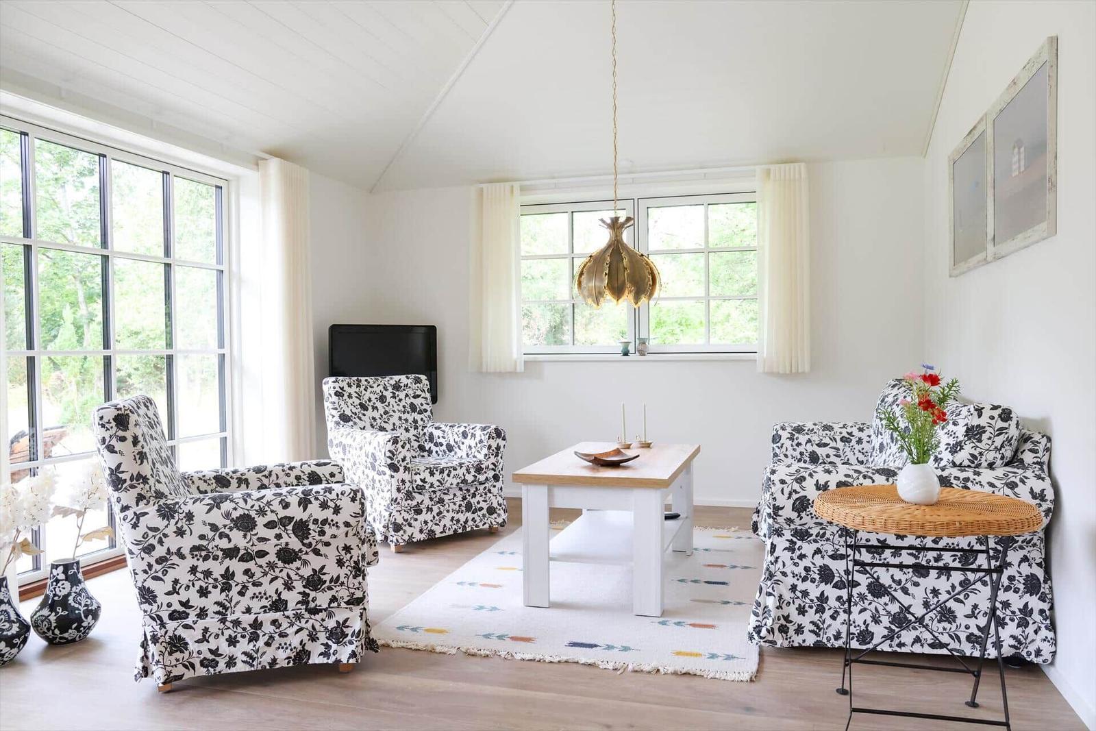 Wohnzimmer mit Sitzgruppe, Tisch und Fenstern.