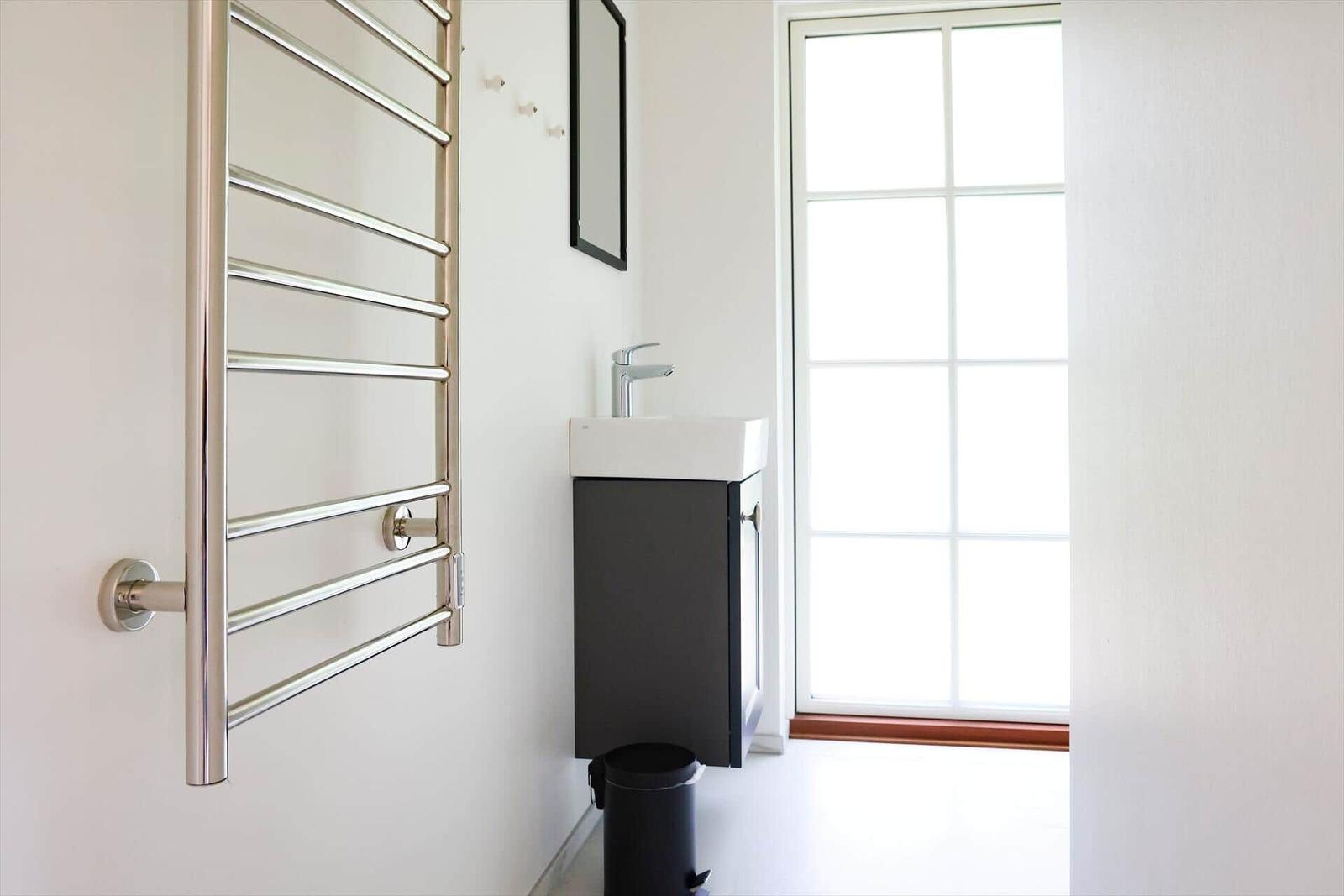 Badezimmer mit Handtuchhalter, Waschbecken und Fenster.