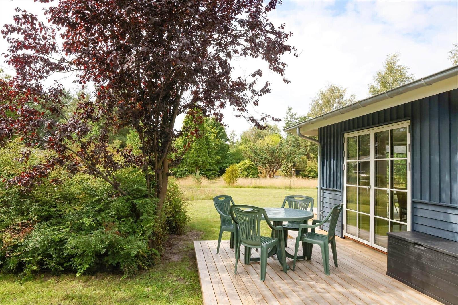 Terrasse mit grünem Tisch und Stühlen neben blauem Haus mit Gartentür.