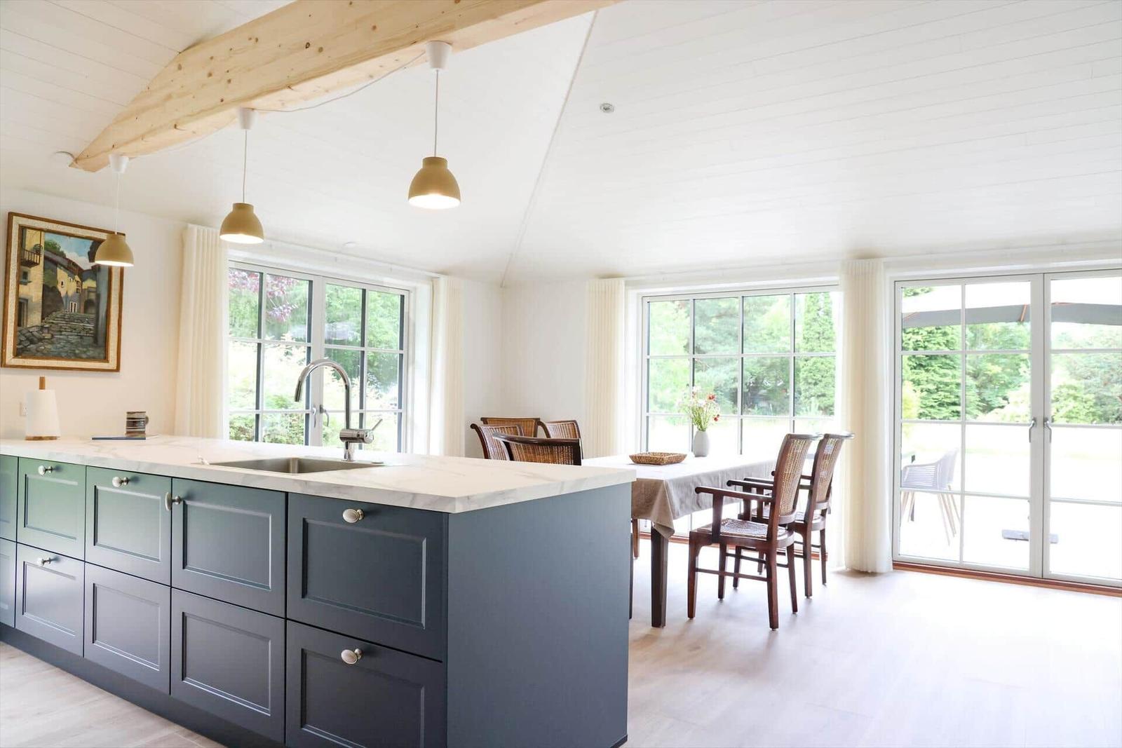 Küche mit Kücheninsel, Essbereich und großzügigen Fenstern.