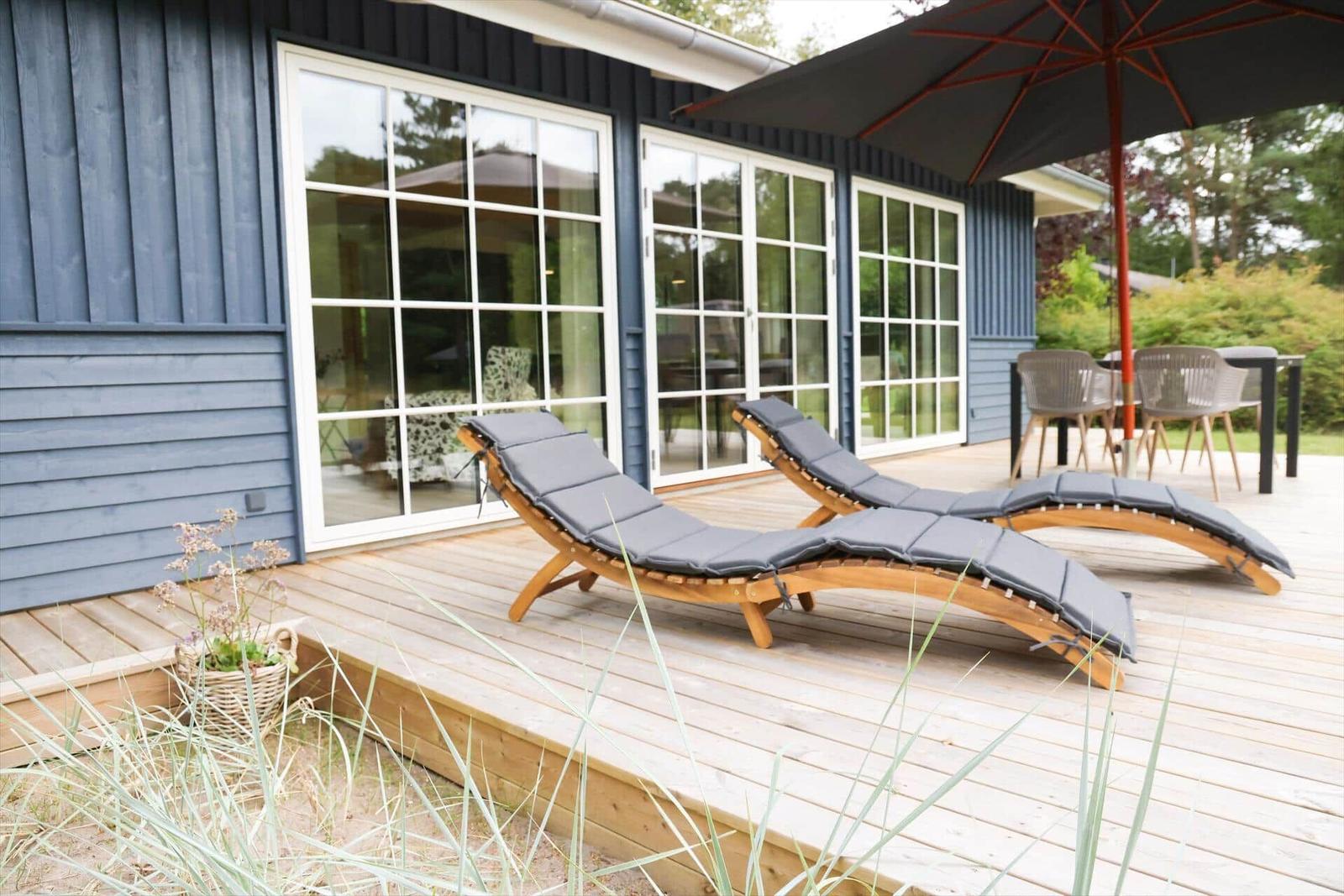Terrasse mit zwei Liegestühlen, Sonnenschirm und Tisch mit Stühlen.