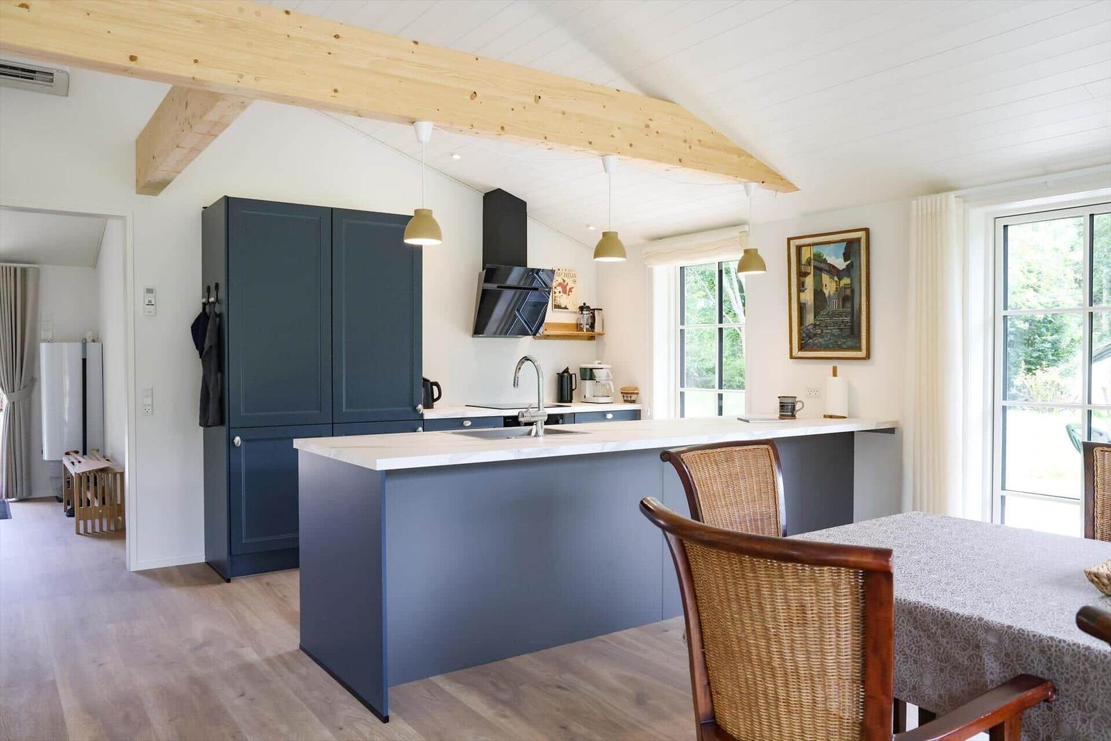 Küche mit dunkelblauen Schränken und Holzbalken an der Decke.