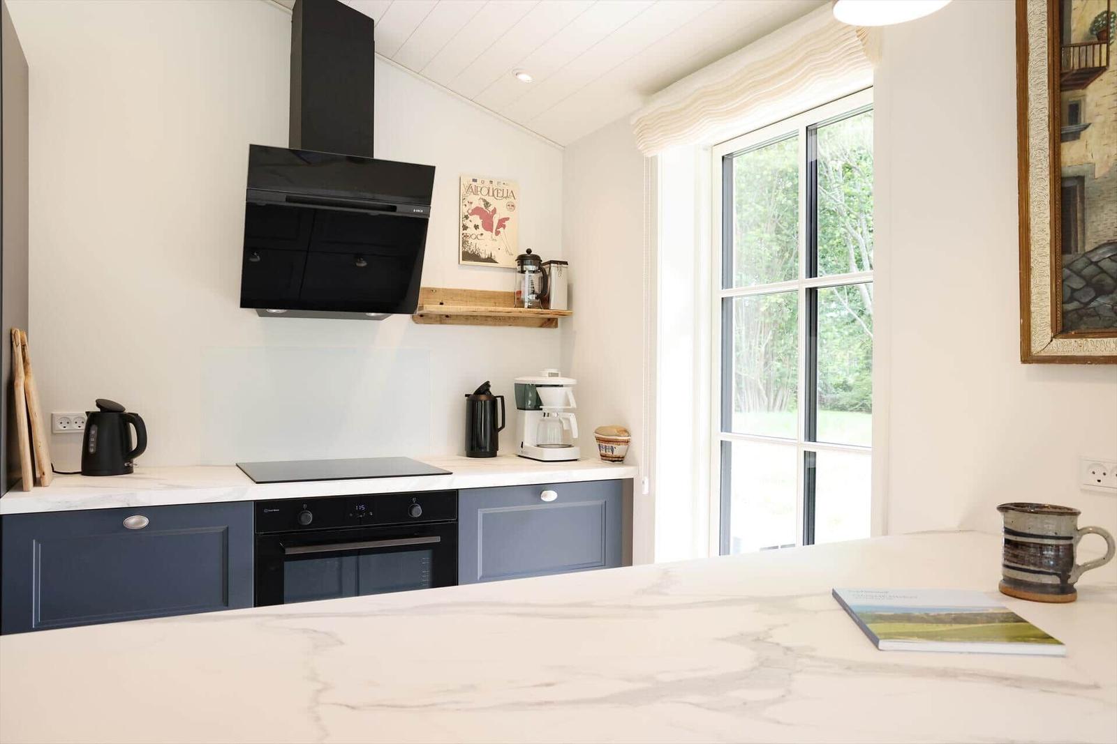 Küche mit Arbeitsplatte, Kochfeld und Fenster zur Aussicht.