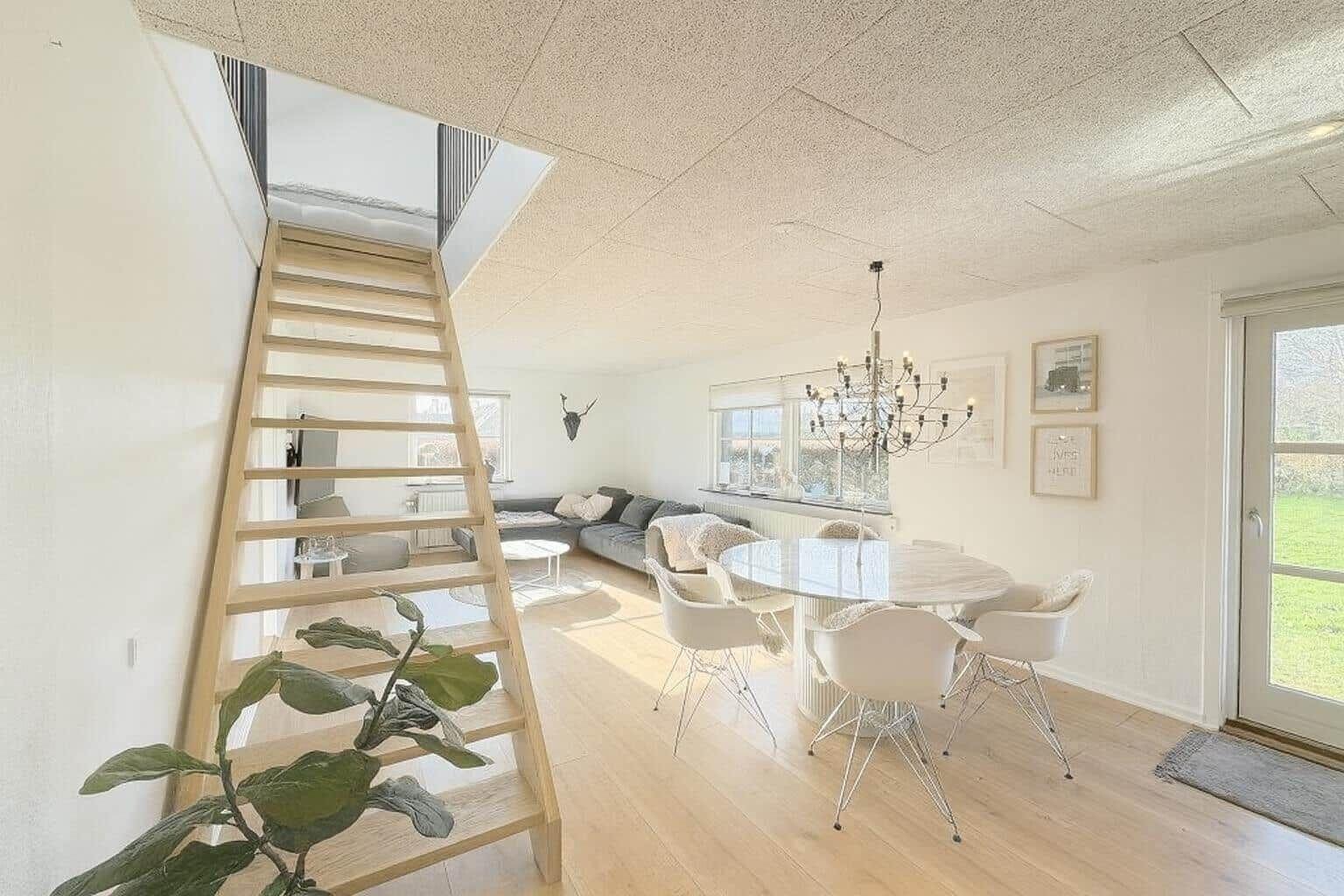 Wohn- und Essbereich mit Holztreppe und Esszimmertisch.