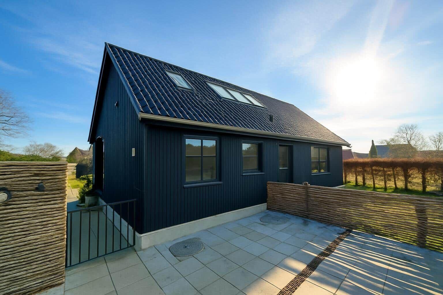 Moderne dunkelblaue Hütte mit Dachfenstern und Steinplattenhof.