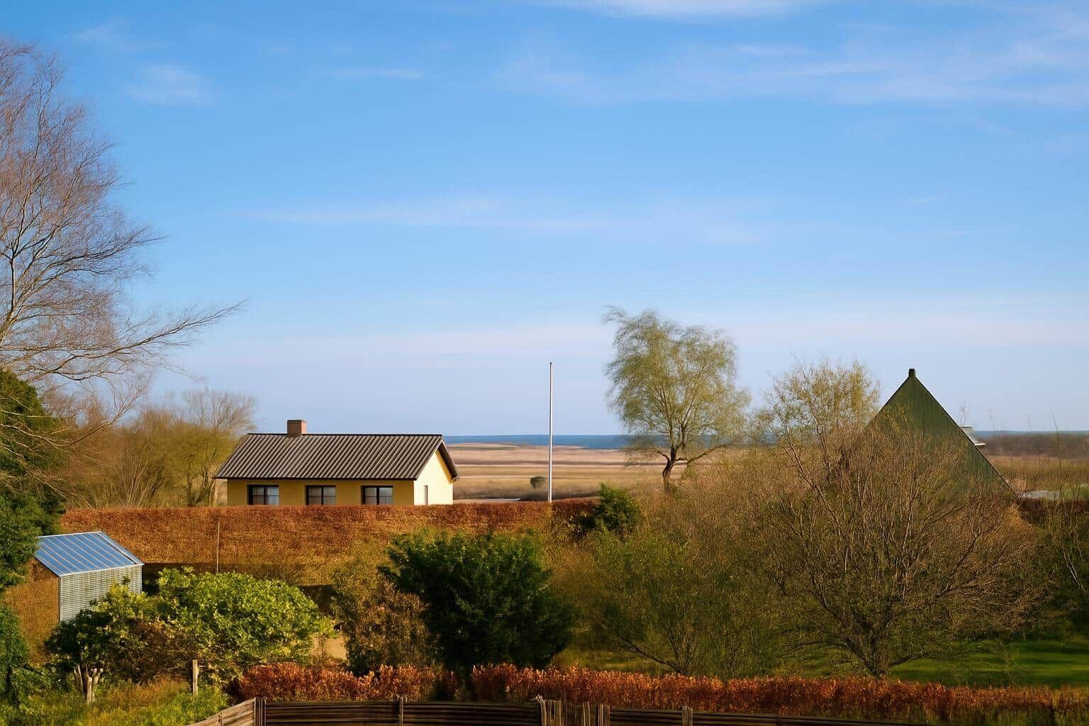 Haus mit Blick auf Meer, umgeben von Bäumen und Feldern.