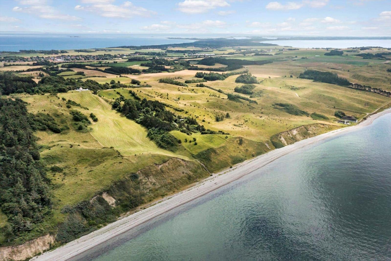 Hügelige Küstenlandschaft mit Strand und Blick aufs Meer.