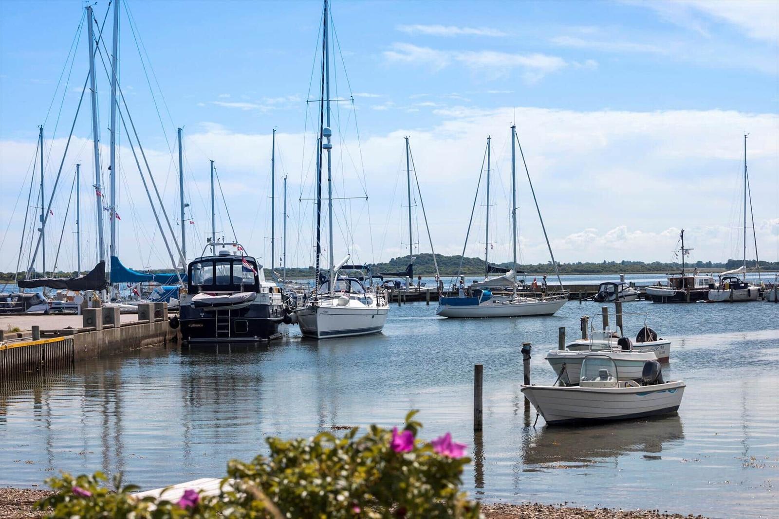 Hafen mit mehreren Segelyachten und Motorbooten unter blauem Himmel.