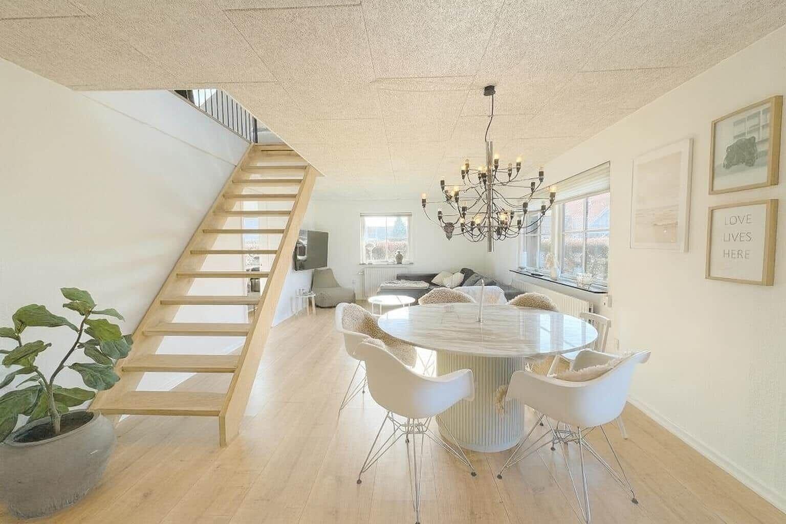 Essbereich mit runder Tisch, Stühlen und Treppe zur oberen Etage.