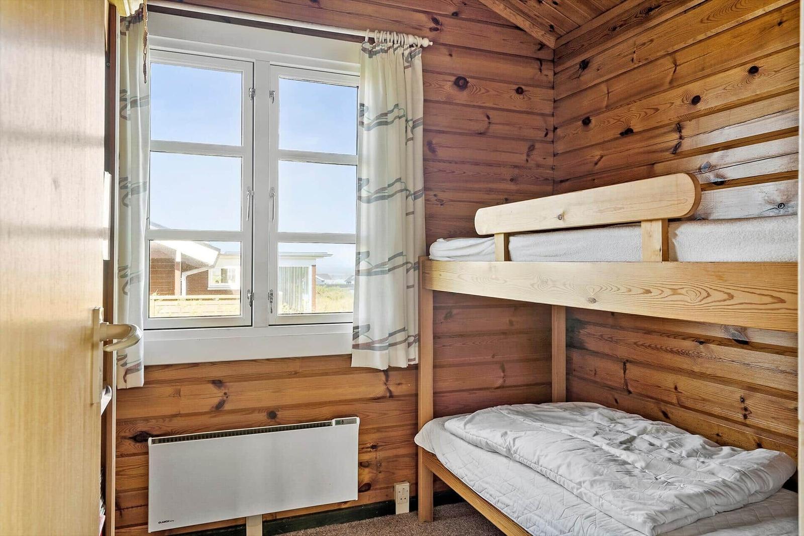 Kabine mit Doppelstockbett, Holzwand und Fenster mit Blick nach draußen.